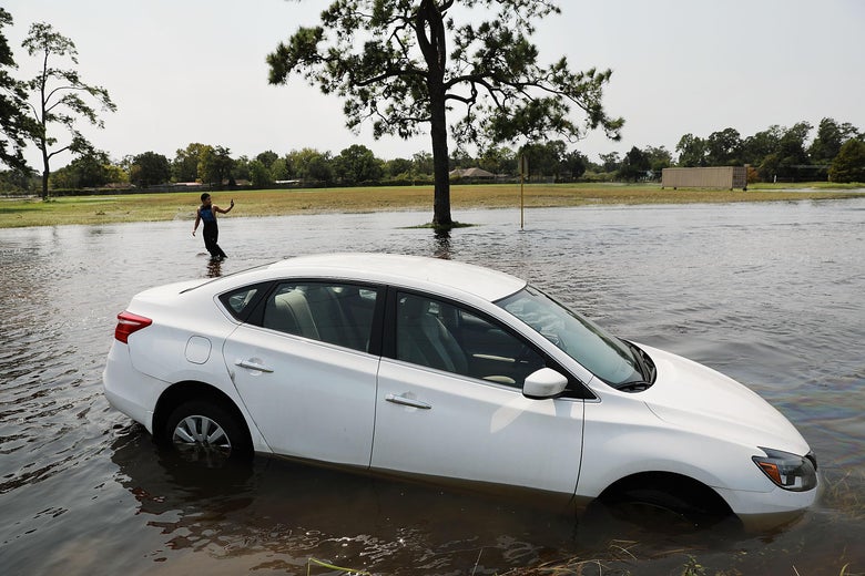ORANGE, TX - SEPTEMBER 06: Juan Aquinaga walks by a submerged car while going to check on his sister's house in Orange as Texas slowly moves toward recovery from the devastation of Hurricane Harvey on September 6, 2017 in Orange, Texas. Almost a week after Hurricane Harvey ravaged parts of the state, some neighborhoods still remained flooded and without electricity. While downtown Houston is returning to business, thousands continue to live in shelters, hotels and other accommodations as they contemplate their future. (Photo by Spencer Platt/Getty Images)